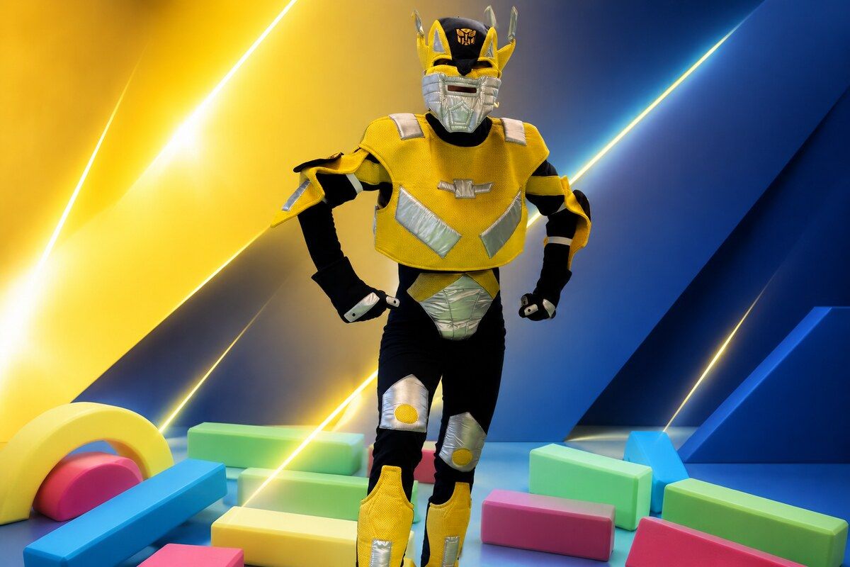 Animator w żółtym kostiumie robota Bumblebee na dynamicznym granatowo-żółtym tle