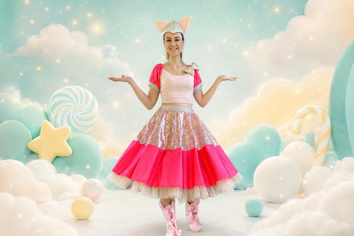Animatorka Kitty Queen w różowym kostiumie na pastelowym, cukierkowym tle