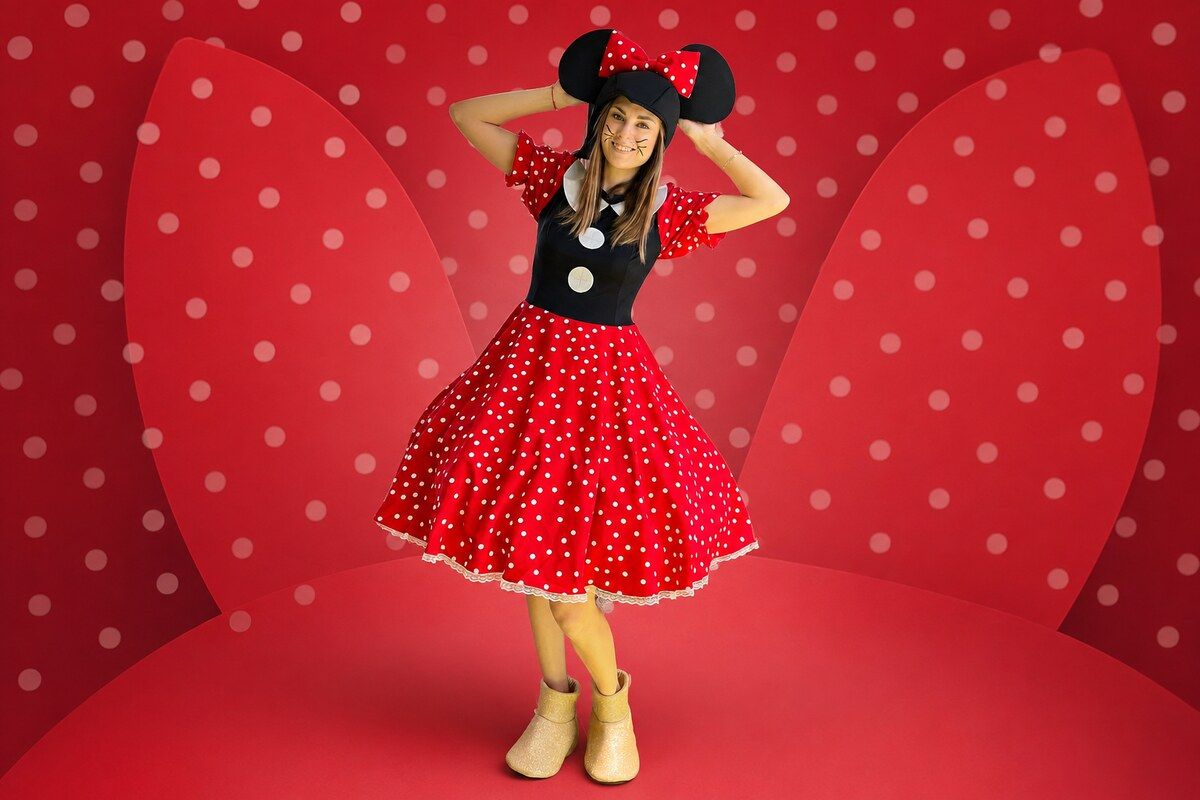 Animatorka w czerwonej sukience w grochy i uszach Minnie na czerwonym tle